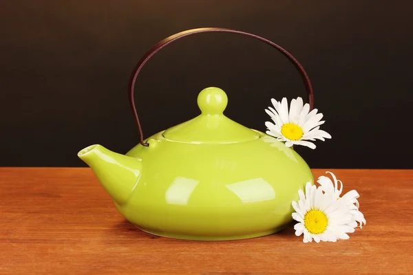 Théière avec thé à la camomille sur table en bois sur fond brun — Photo