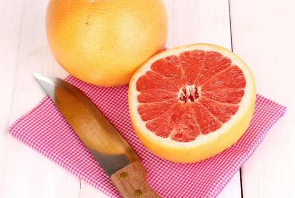 Спелый грейпфрут и половина на салфетке на деревянном фоне — стоковое фото