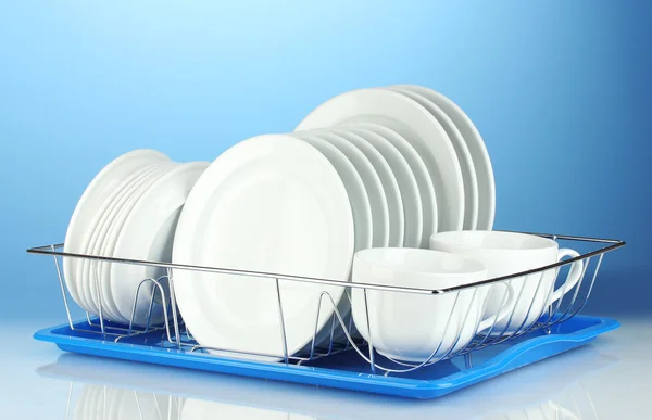 Czyste naczynia na stojak na niebieskim tle — Zdjęcie stockowe