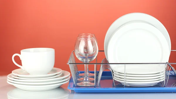 Czyste naczynia na stojak na czerwonym tle — Zdjęcie stockowe