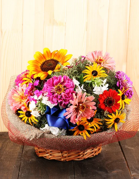 Beautiful bouquet of bright flowers in sacking on wooden background — Stock Photo, Image
