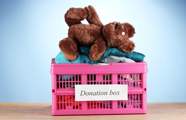 Donation box with clothing on blue background close-up — Stock Photo, Image