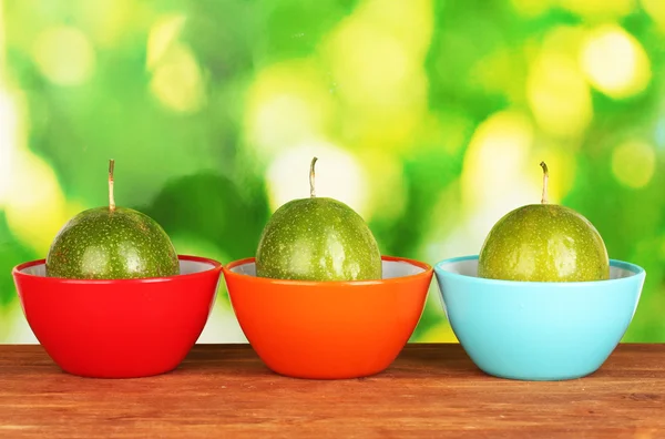 Три зеленых фрукта маракуйи в мисках на зеленом фоне — стоковое фото