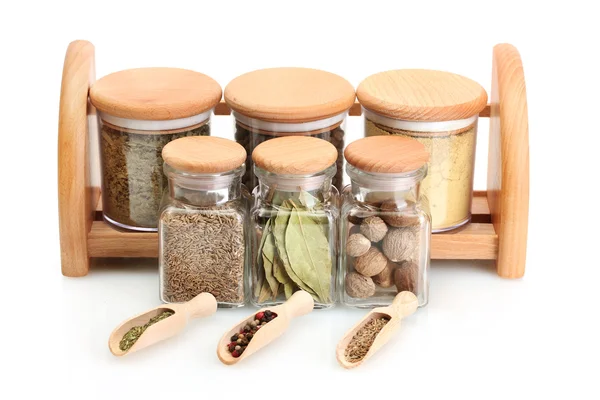 Jars and wooden spoons on shelf with spices isolated on white — Stock Photo, Image