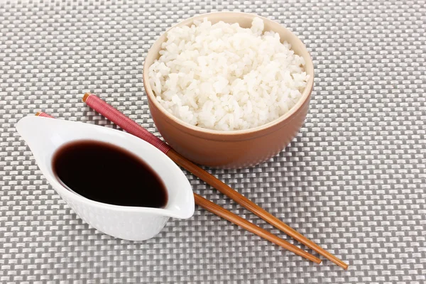 Kom rijst en eetstokjes op grijs mat — Stockfoto