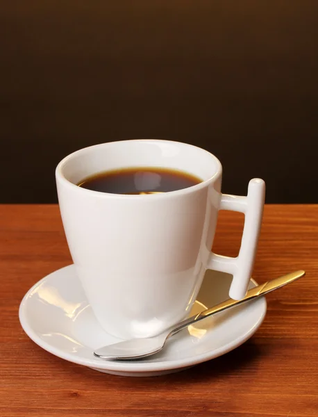 Koffiekopje op houten tafel op bruine achtergrond — Stockfoto