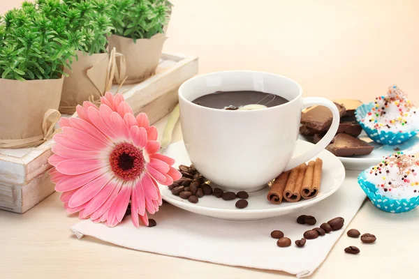 Csésze kávé és a bab gerbera, a fahéj botokkal a fából készült asztal — Stock Fotó