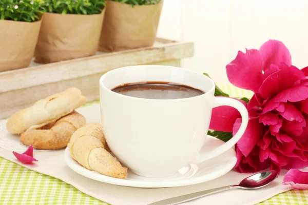 Šálek horké čokolády, sušenky a květiny na stole v kavárně — Stock fotografie