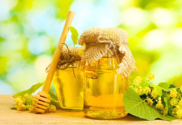 Borcane cu miere de in si flori pe masa de lemn pe fundal verde — Fotografie, imagine de stoc