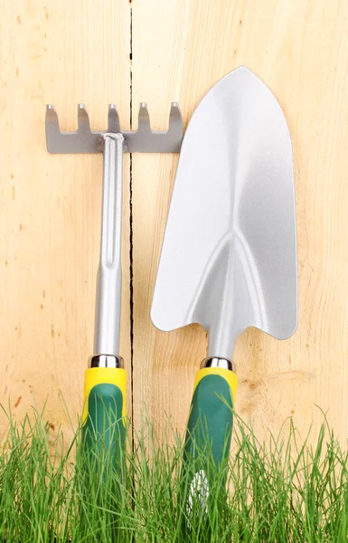 Zielona trawa i narzędzia ogrodowe na drewniane tła — Zdjęcie stockowe
