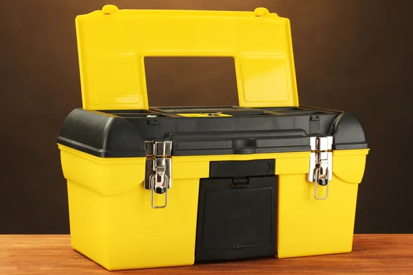 Открыть желтую коробку инструментов на коричневом фоне крупным планом — стоковое фото