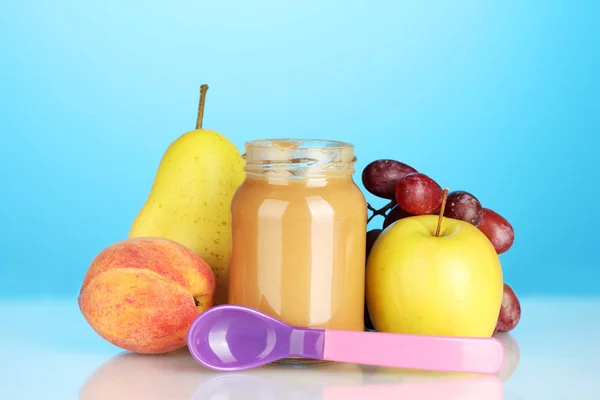 Glas mit Obst Babynahrung und Löffel auf buntem Hintergrund — Stockfoto