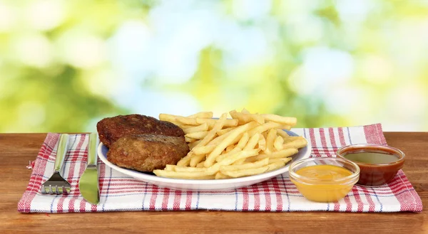 Potatis pommes frites med hamburgare på plattan på grön bakgrund närbild — Stockfoto
