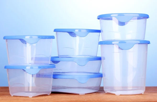 蓝色背景上的木桌子上的食物的塑料容器 — 图库照片