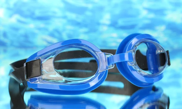 Lunettes de bain bleues avec des gouttes sur fond bleu mer — Photo