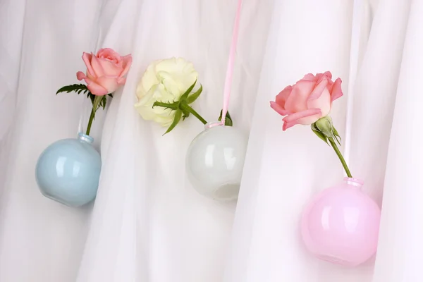 Красивые розы в вазах висят на тканном фоне — стоковое фото