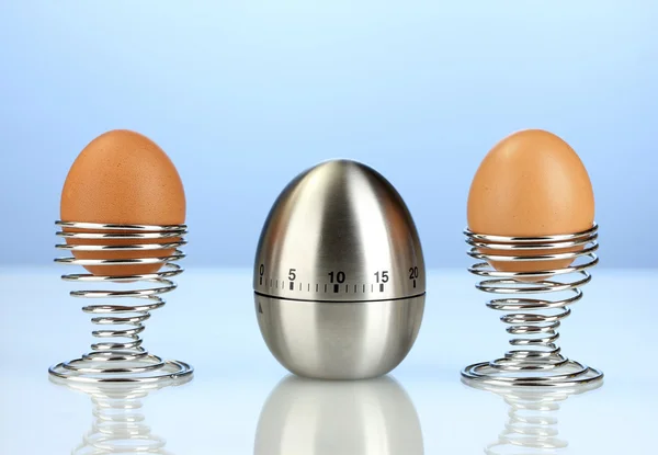 Temporizador de ovo e ovo em suporte de metal no fundo azul — Fotografia de Stock