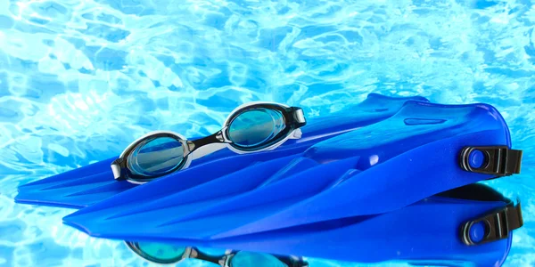 Chinelos e óculos azuis no fundo do mar azul — Fotografia de Stock