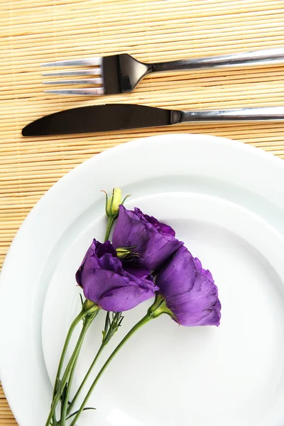 Tableware with flower on bamboo mat close-up — Stock Photo, Image