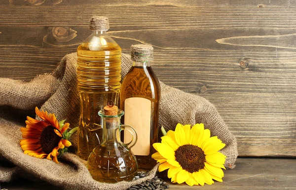 Aceite en botellas, girasoles y semillas, sobre fondo de madera — Foto de Stock