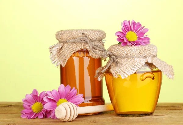 Miel dulce en frascos con rociador sobre mesa de madera sobre fondo verde —  Fotos de Stock
