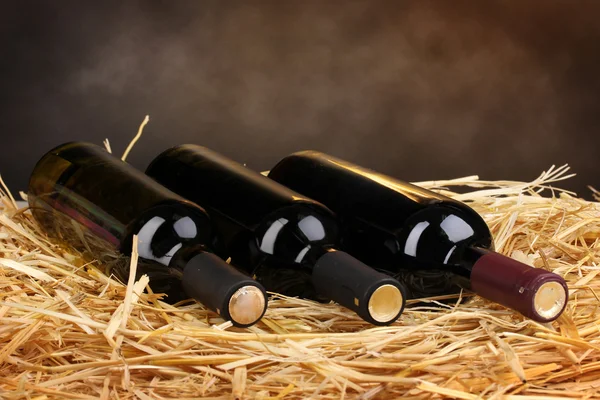 Пляшки великого вина на сіні на коричневому фоні — стокове фото