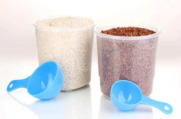 Cucharas de medir y recipientes de plástico con grano aislado en blanco —  Fotos de Stock
