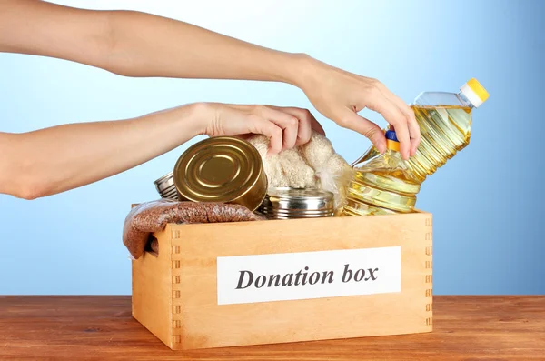 Caixa de doação com alimentos em fundo azul close-up — Fotografia de Stock