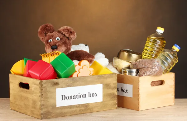 Donation box with food and children's toys on brown background close-up — Stock Photo, Image