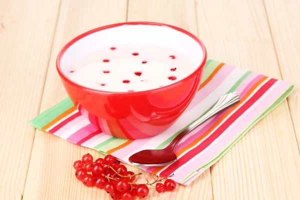 Yogur con grosella roja sobre mesa de madera — Foto de Stock