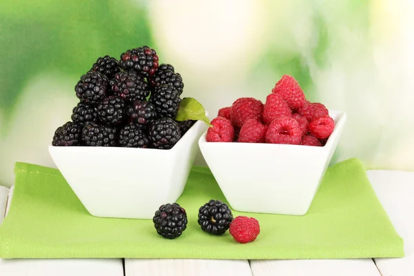 Ripe raspberries and brambles on wooden table on nature background — Stock Photo, Image