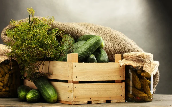 Färska gurkor i trälåda, pickles och dill, på grå bakgrund — Stockfoto