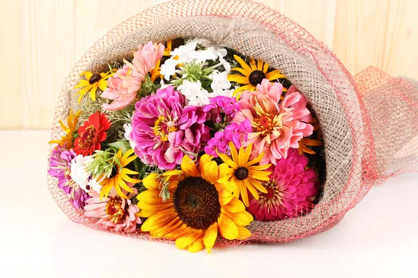 stock image Beautiful bouquet of bright flowers in sacking on wooden background