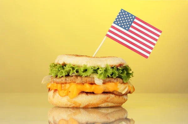 Sanduíche saboroso com bandeira americana, no fundo amarelo — Fotografia de Stock