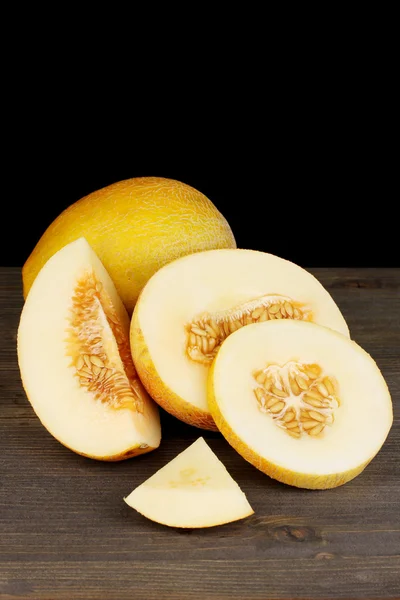 Cortar melones maduros sobre mesa de madera sobre fondo negro — Foto de Stock