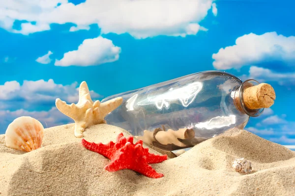 Botella de vidrio con nota en el interior sobre arena, sobre fondo azul cielo — Foto de Stock