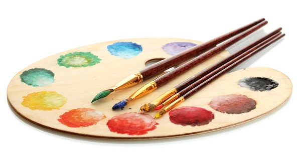 Деревянная художественная палитра с краской и кисточками, изолированные на белом — стоковое фото