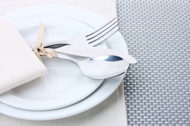 beyaz boş tabak çatal, kaşık ve bıçak ile bir şerit üzerinde gri bir masa örtüsü ile bağlıdır.