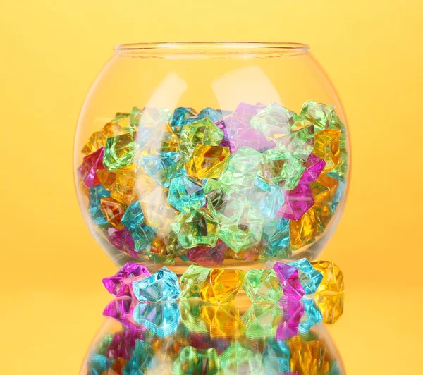 Ein Glas mit bunten Schmucksteinen auf gelbem Hintergrund Nahaufnahme — Stockfoto
