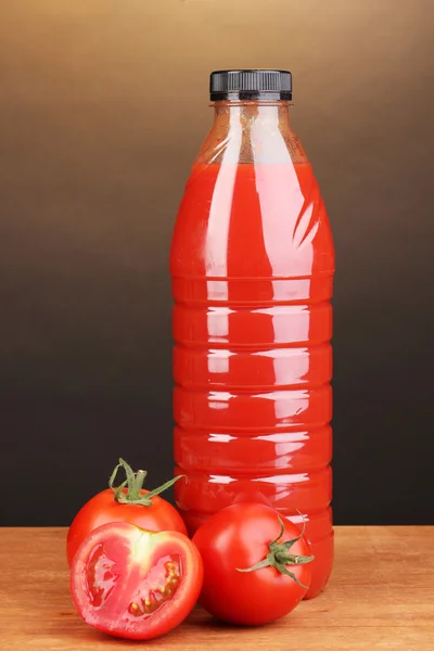 Jus de tomate en bouteille sur table en bois sur fond brun — Photo