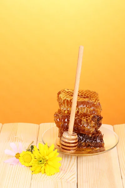 Honungskaka på träbord på orange bakgrund — Stockfoto