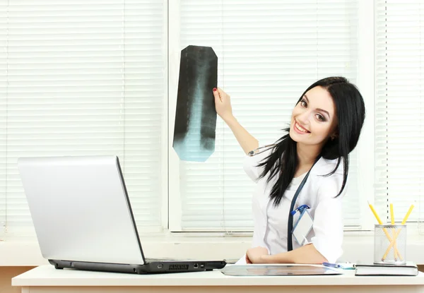 Όμορφη κοπέλα γιατρός κρατώντας ακτινογραφία στο γραφείο — Φωτογραφία Αρχείου