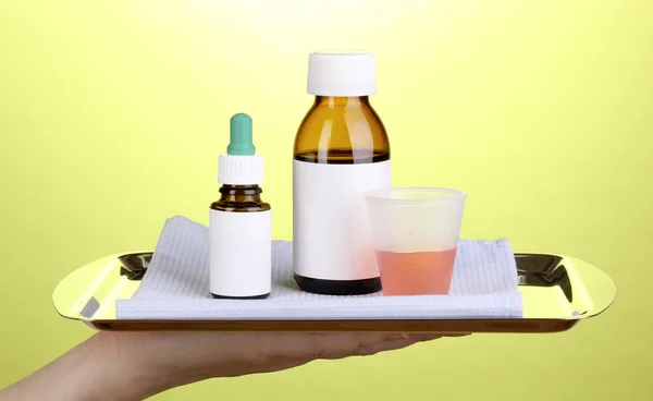 Ruka drží tác s léky na zeleném pozadí — Stock fotografie