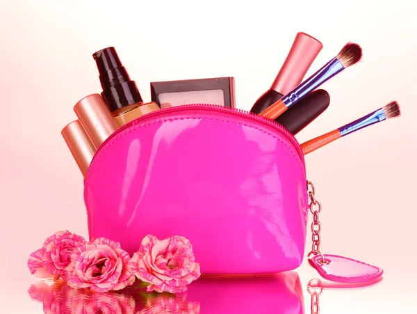 Макияж мешок с косметикой и щетки на розовом фоне — стоковое фото