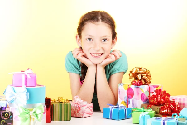 Маленька дівчинка з подарунками на жовтому тлі — стокове фото