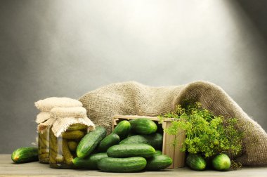 Fresh cucumbers in wooden box, pickles and dill, on grey background clipart