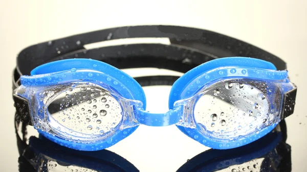Occhiali da bagno blu con gocce su sfondo grigio — Foto Stock