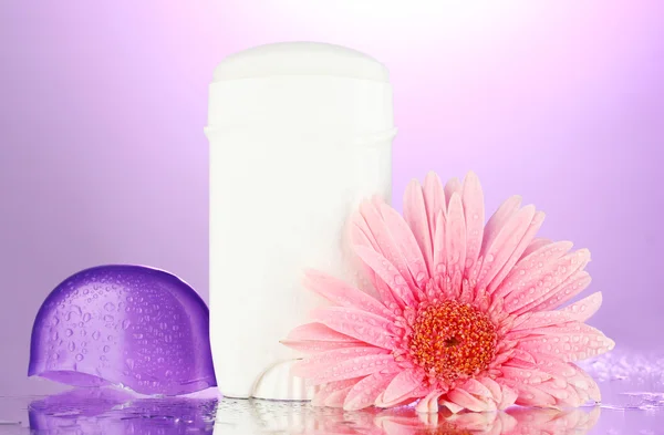 Deodorant with flower on purple background — Stock Photo, Image