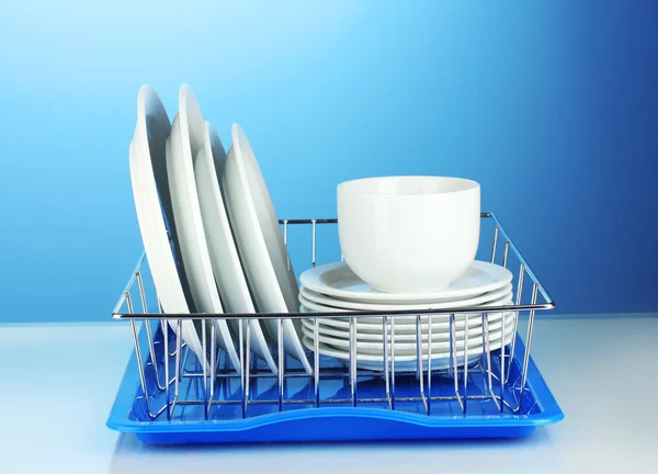 Czyste naczynia na stojak na niebieskim tle — Zdjęcie stockowe