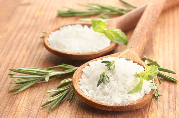 Salt in spoons with fresh basil, thyme and rosemary isolated on white